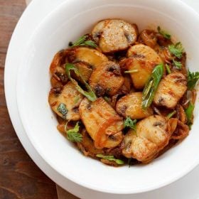 mushroom stir fry garnished with coriander leaves and served in a white bowl.