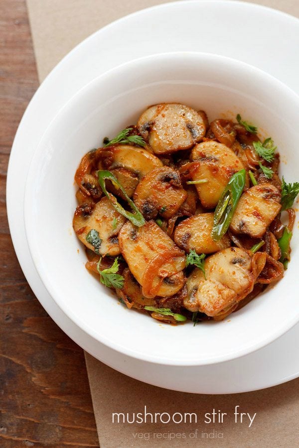 mushroom stir fry garnished with coriander leaves and served in a white bowl.