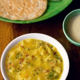 potato sagu served in a white bowl with a plate of dosas, a small bowl of coconut chutney and text layovers.