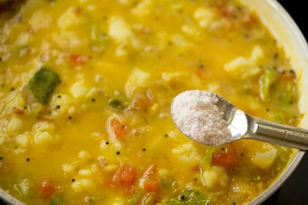 adding salt to the potato curry. 