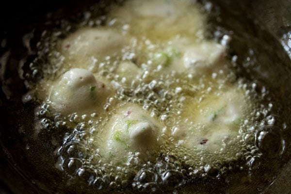 large spoonfuls of punugulu batter added to the hot oil.