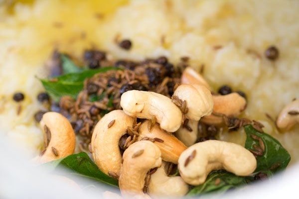 the fried tempering cashews, curry leaves, cumin and black pepper ghee mixture on the cooked rice and lentils