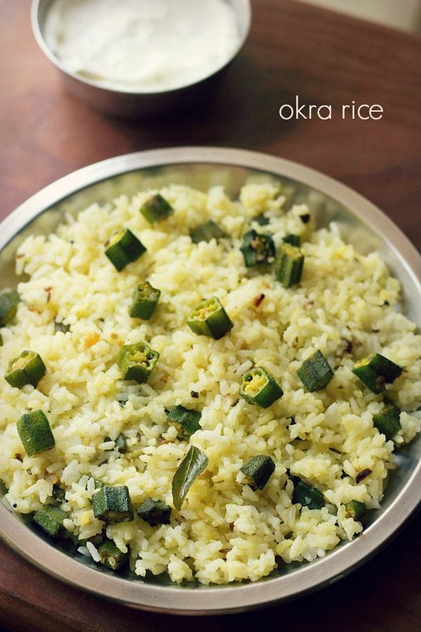 bhindi rice served on a steel plate with a side of plain curd.