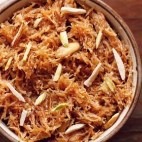 meethi seviyan garnished with almond slivers and served in a brown rimmed ceramic bowl.