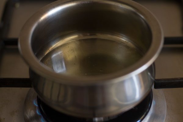 sesame oil being heated in a small steel pan for the tempering of the instant mango pickle.  