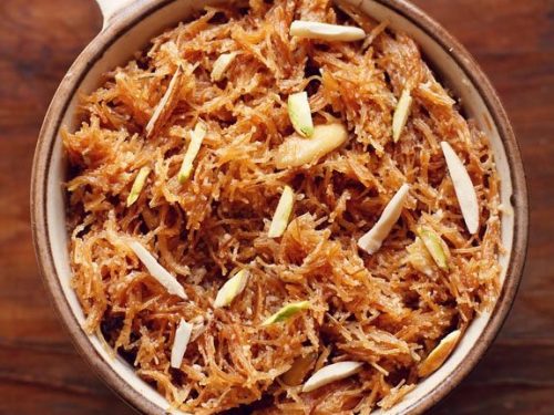 meethi seviyan garnished with almond slivers and served in a brown rimmed ceramic bowl.