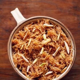 meethi seviyan garnished with almond slivers and served in a brown rimmed bowl with text layover.