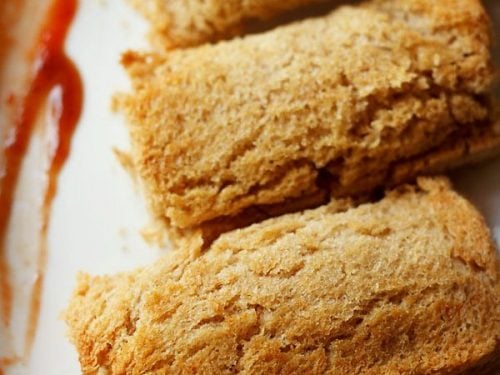 paneer bread roll served on a plate with some tomato ketchup on the side.
