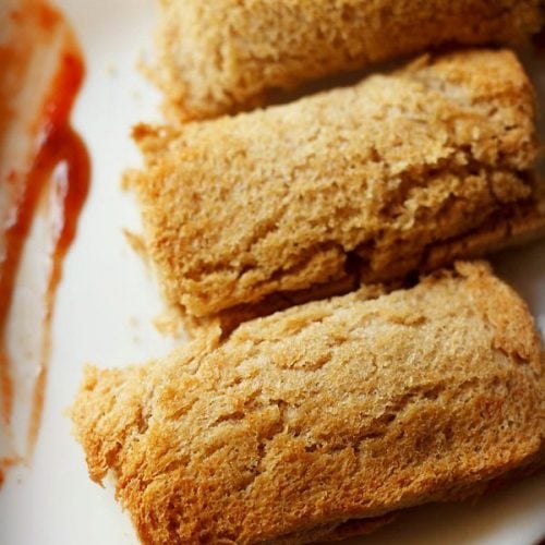 paneer bread roll served on a plate with some tomato ketchup on the side.