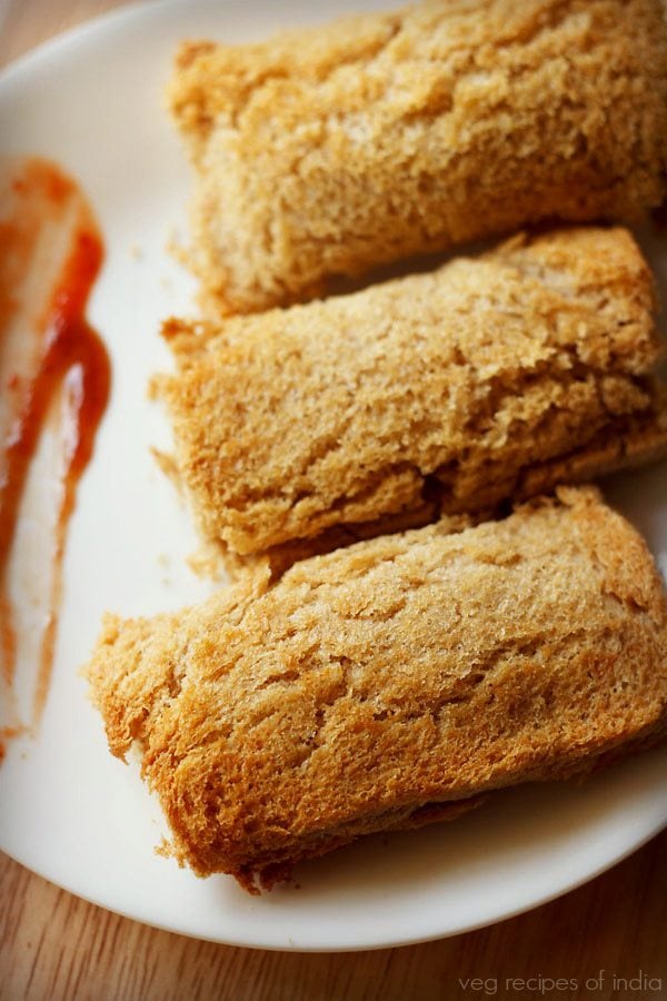 paneer bread roll served on a plate with some tomato ketchup on the side.