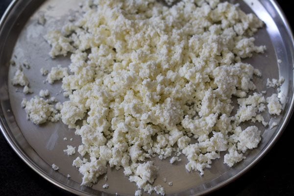 crumbled paneer on a steel plate. 