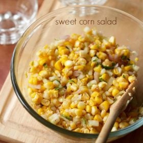 corn salad served in a glass bowl with a wooden spoon in it and text layover.