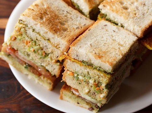 club sandwiches squares with layers seen on a white plate
