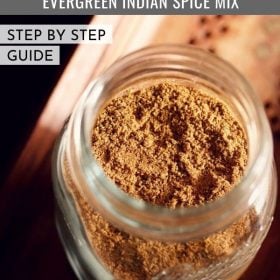 garam masala in a glass jar on a brown wooden tray.