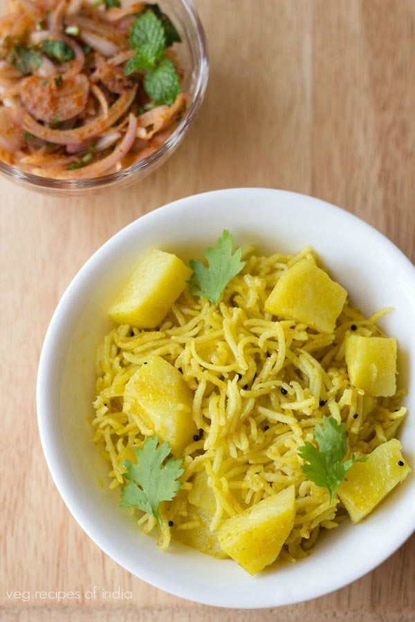 potato pulao served on a white plate with a side of onion salad