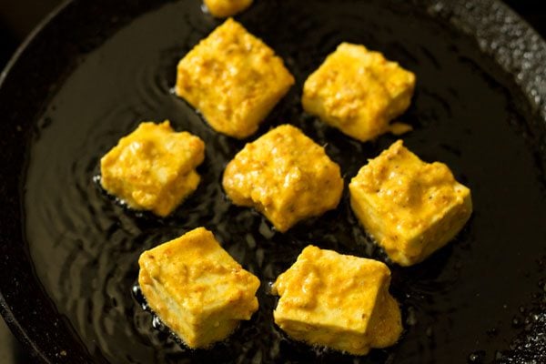 marinated paneer cubes placed in hot oil. 