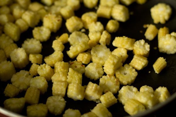 sautéing baby corn in pan. 