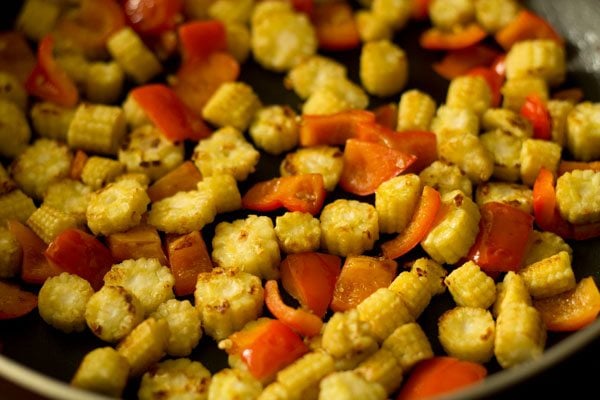 sautéing baby corn and red bell pepper in the pan. 