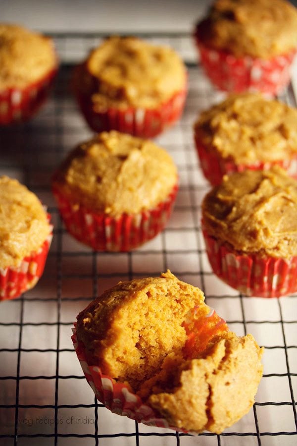 mango muffins placed on a wired tray with a mango muffin halved to show the texture.