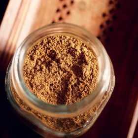 garam masala powder in a glass jar on a brown wooden tray