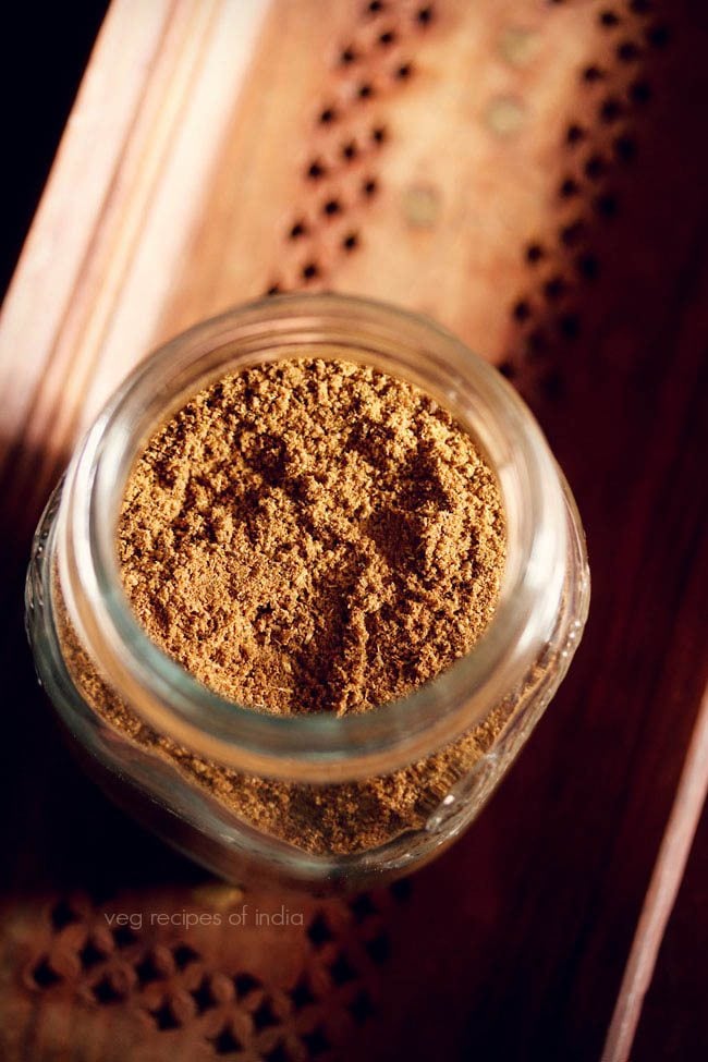 garam masala powder in a glass jar on a brown wooden tray