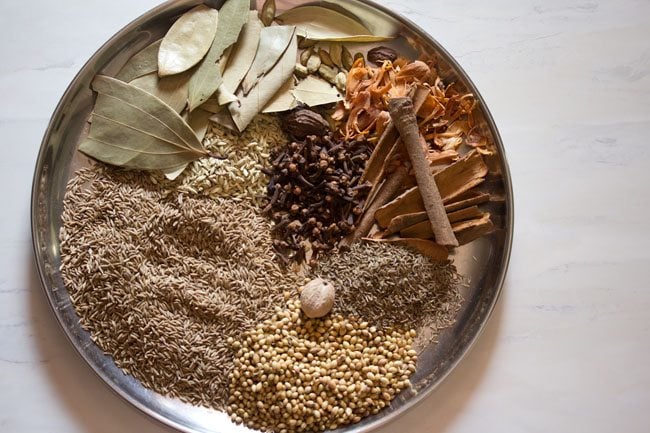 whole spices arranged on a steel plate.