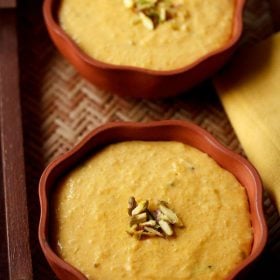 mango phirni garnished with sliced pistachios and served in small earthen bowls.