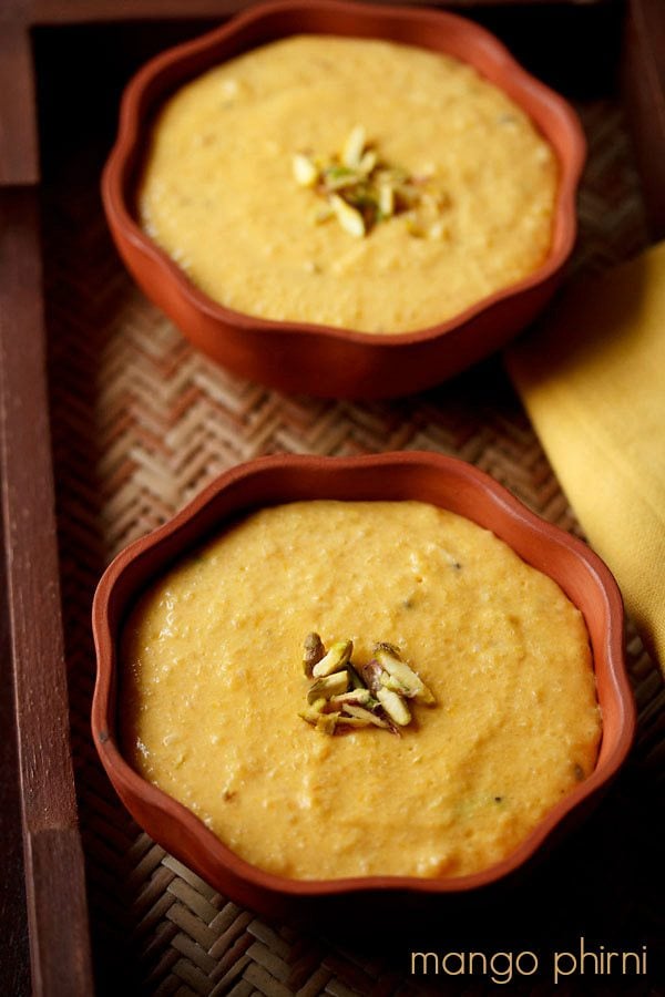 mango phirni garnished with sliced pistachios and served in small earthen bowls.