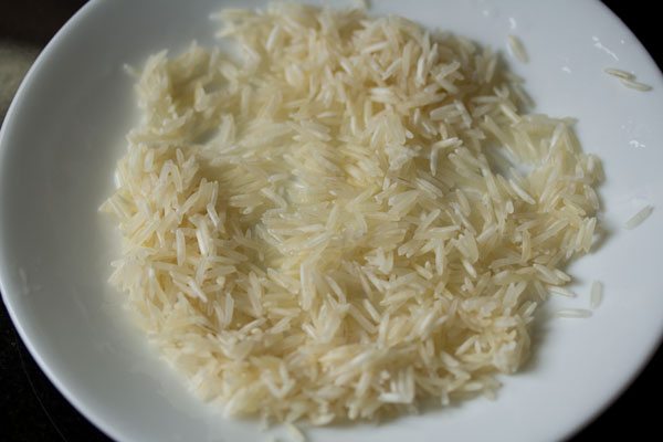 rinsed basmati rice grains spread on a plate to dry. 