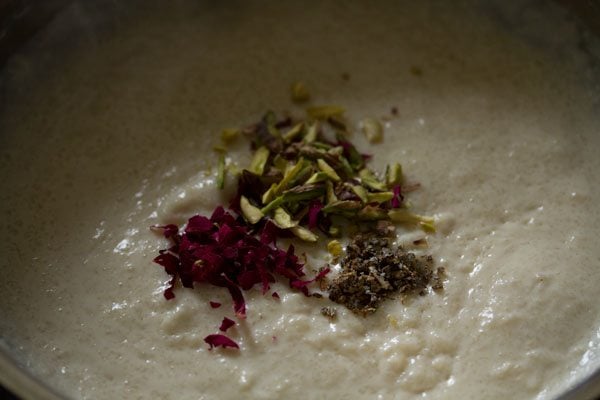 adding sliced pistachios, cardamom powder and chopped dried rose petals in the phirni mixture. 
