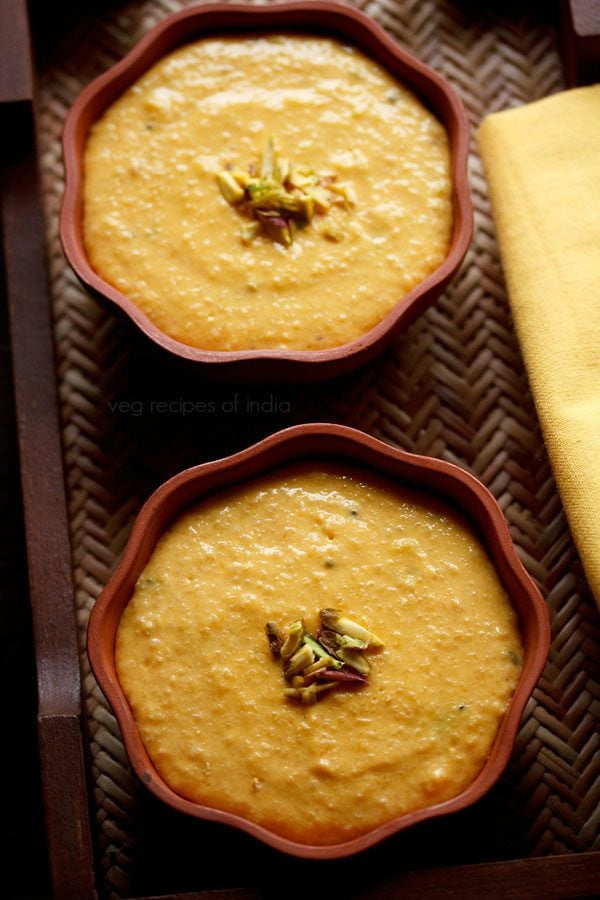 mango phirni garnished with sliced pistachios and served in small earthen bowls. 