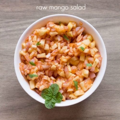 raw mango salad garnished with a mint sprig and served in a white bowl with text layovers.