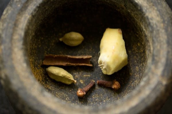 Cinnamon, green cardamoms, 2 cloves and 1-inch ginger in a mortar