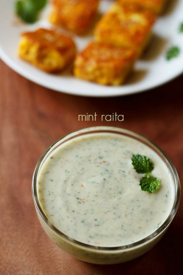 mint raita garnished with a mint sprig and served in a glass bowl with text layover.