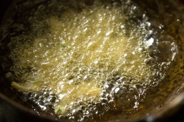 frying onion fritters in hot oil in a kadai