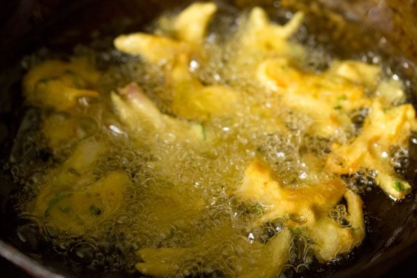 frying onion fritters in hot oil in a kadai