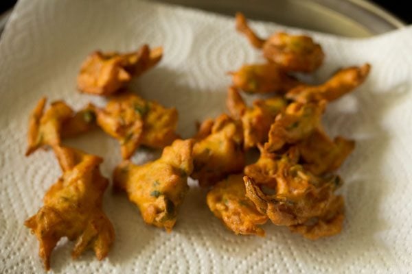 fried onion fritters placed on kitchen paper towel. 