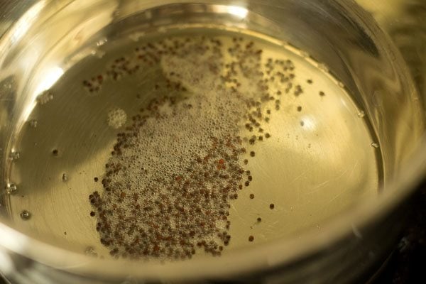 mustard seeds crackling in hot oil in pan. 