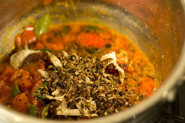 prepared spice mix added to pan for making milagu rasam. 