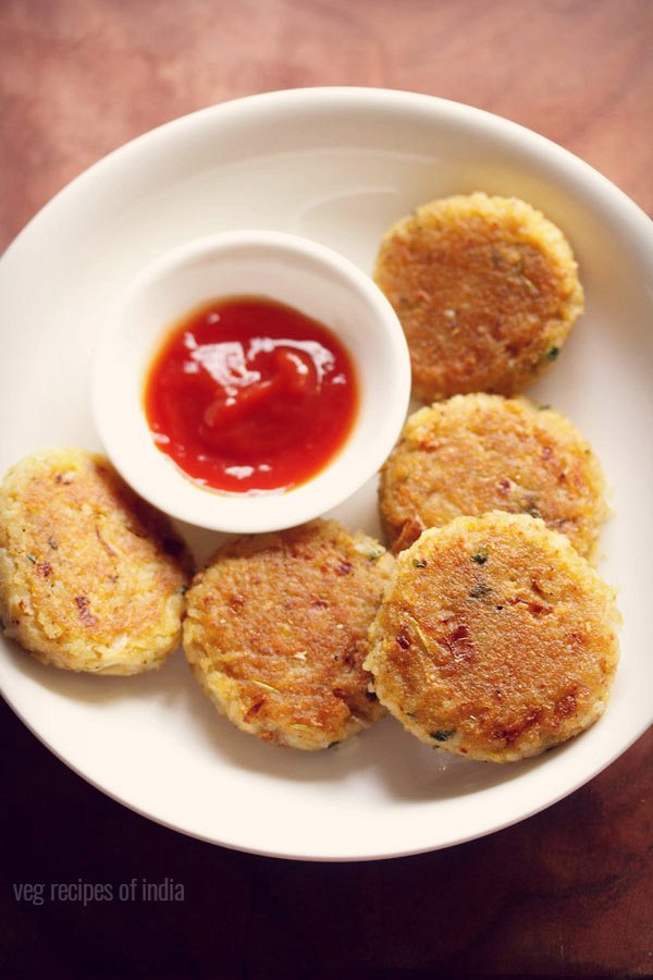 rice cutlet served on a white plate with a small bowl of tomato ketchup kept on the center of the plate and text layover. 