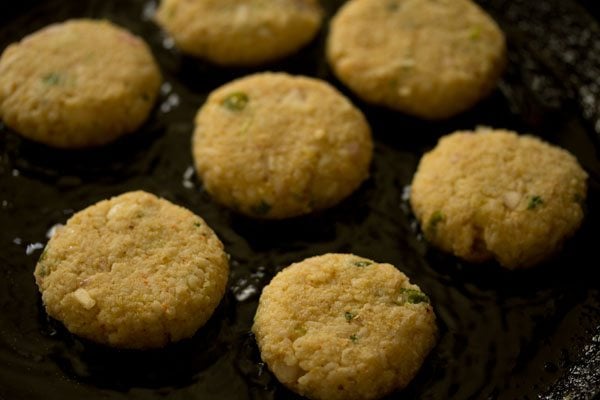 prepared cutlets placed on hot oil on a tawa. 