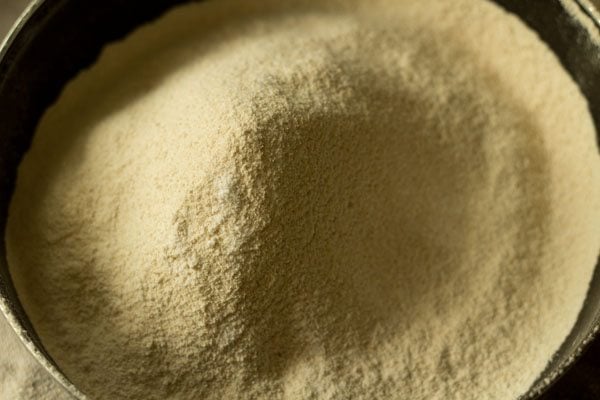 sieving whole wheat flour and rock salt in a bowl for making pastry for baked samosa. 