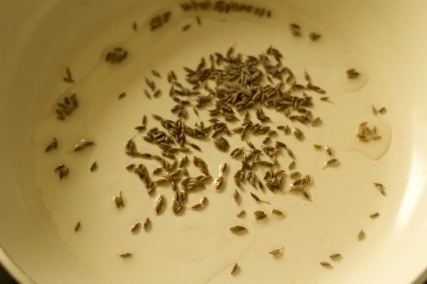 sautéing cumin seeds in hot oil in a pan. 