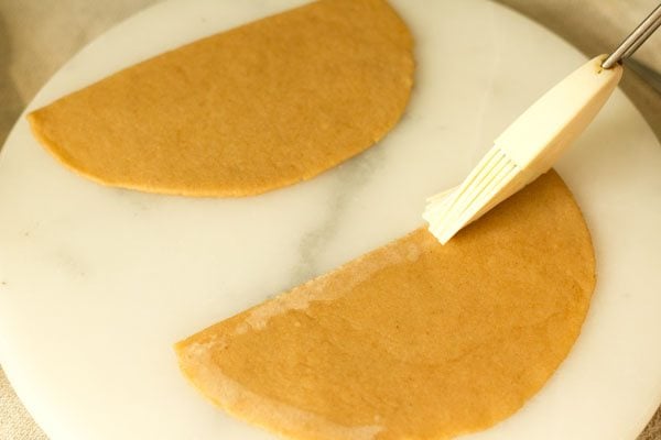 applying water with a brush on the edge of a sliced dough part. 