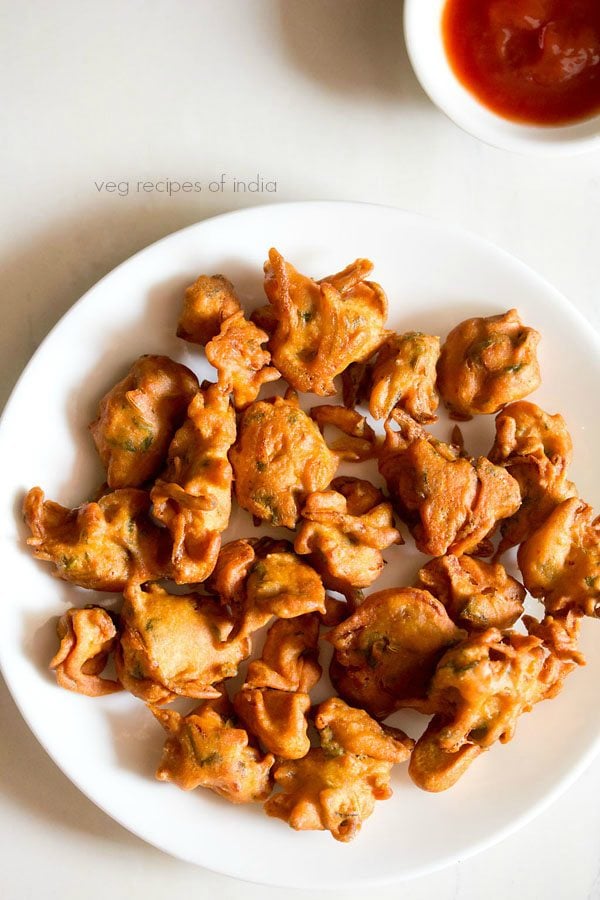 onion fritters served on a white plate with a side of tomato sauce