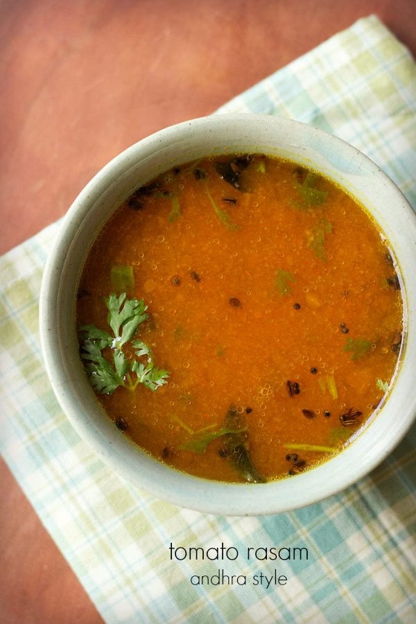 tomato charu with a coriander leaf in a light green ceramic bowl on a light green-blue-white checkered napkin