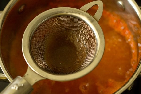 tamarind pulp being added through a small strainer