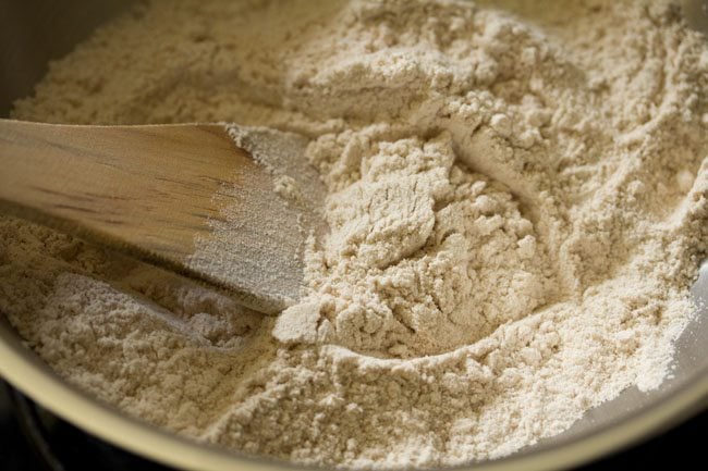 tostar harina de trigo integral en la sartén para atta ke laddu. 