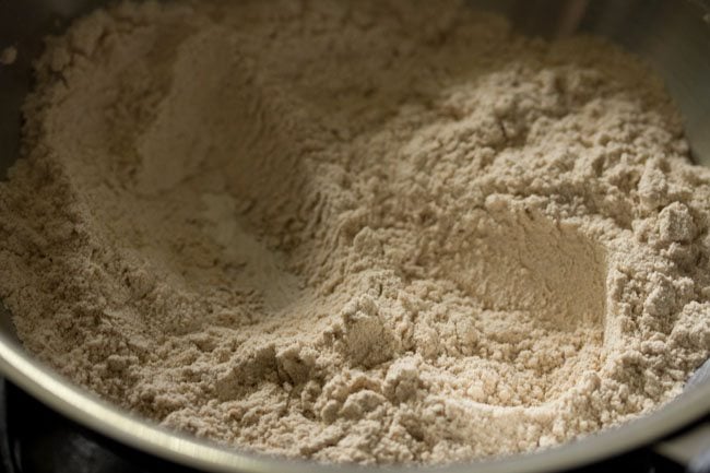 Roast wholemeal flour in the pan for Atta Ke Laddu. 