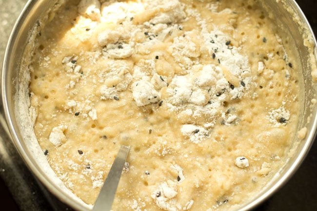 mixing sesame seeds and rice flour well into the sugar solution for banana appam. 